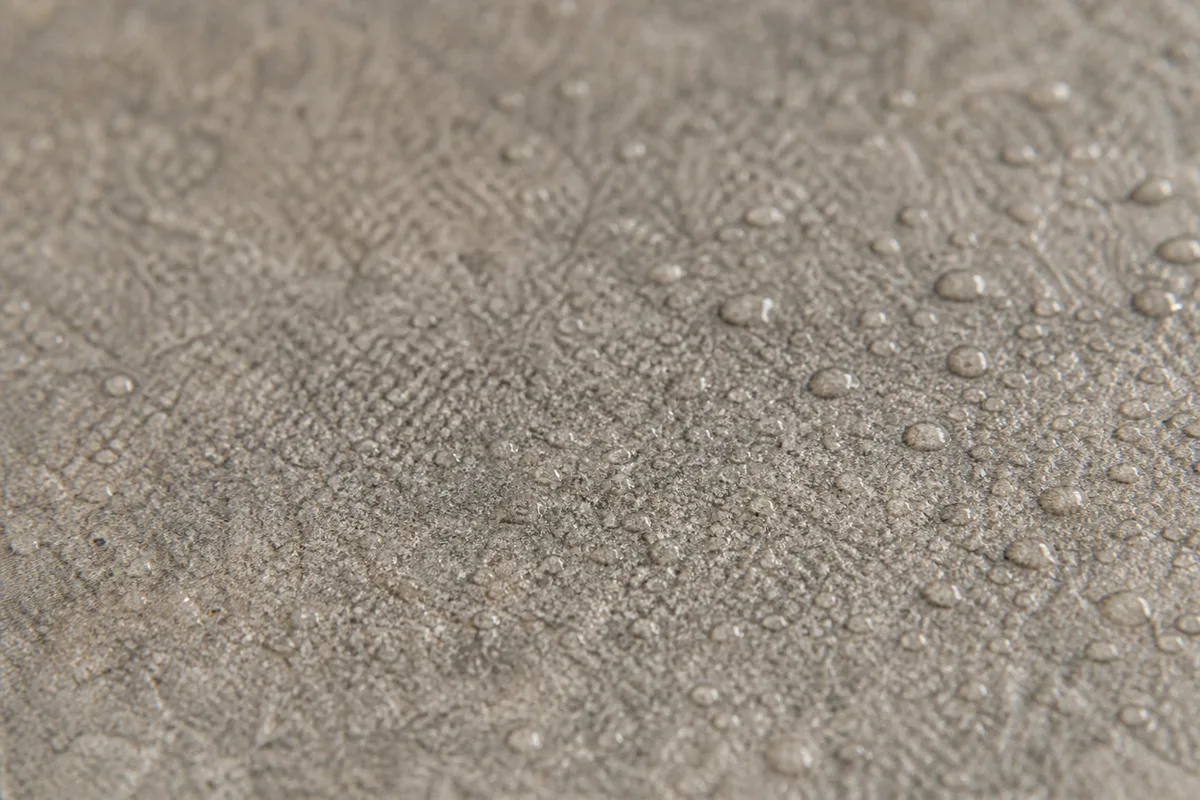 Gros plan sur la surface texturée d&rsquo;un carrelage en grès cérame antidérapant avec des gouttes d&rsquo;eau perlées