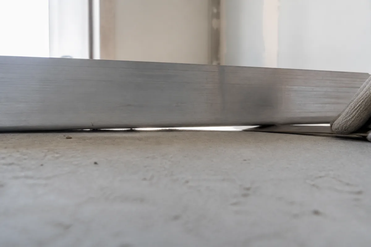 Regle de deux metres posee sur une dalle beton avec un jour de lumiere visible